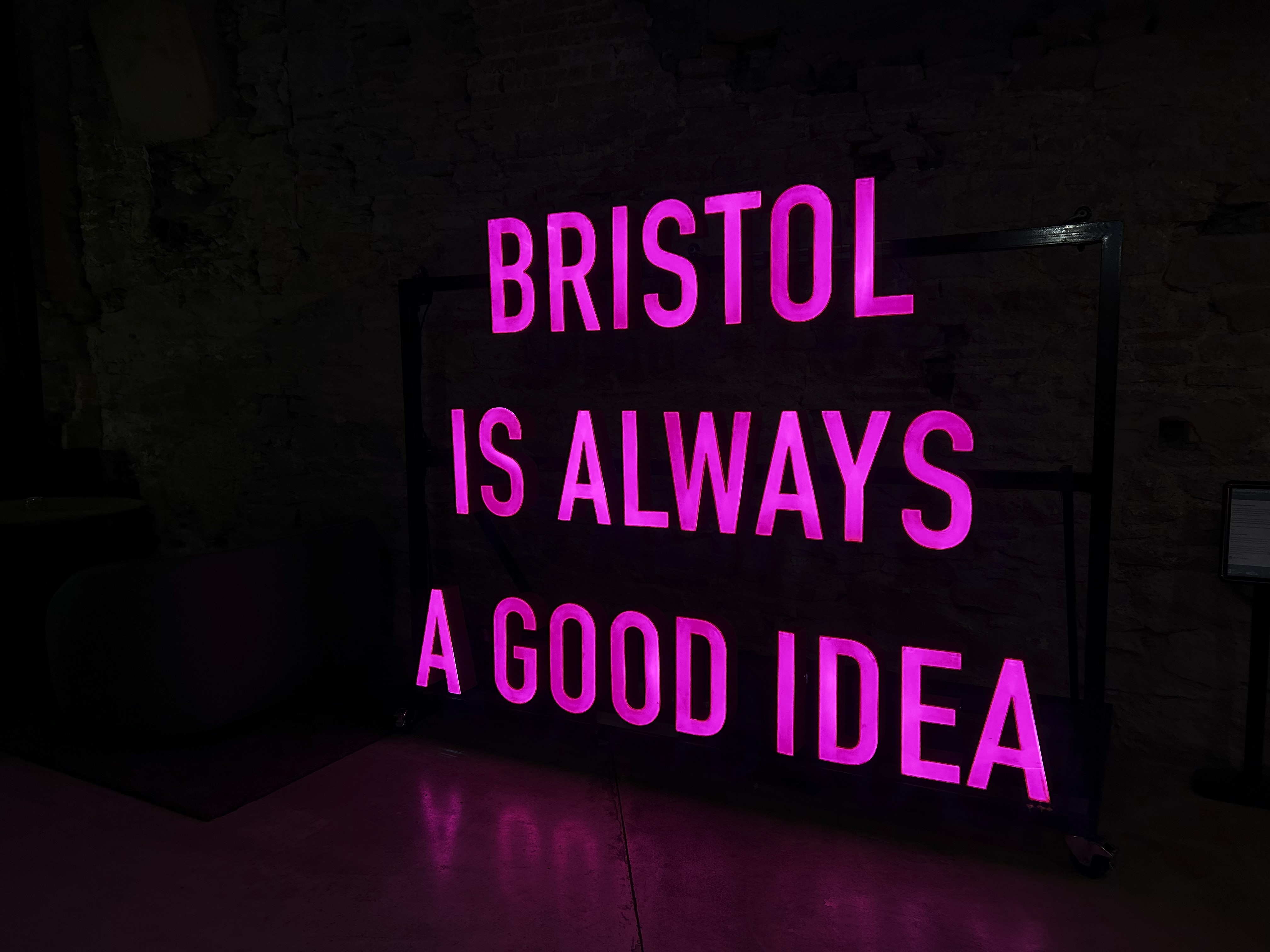 A photo of a light up sign reading "Bristol is always a good idea" in large pink lettering.