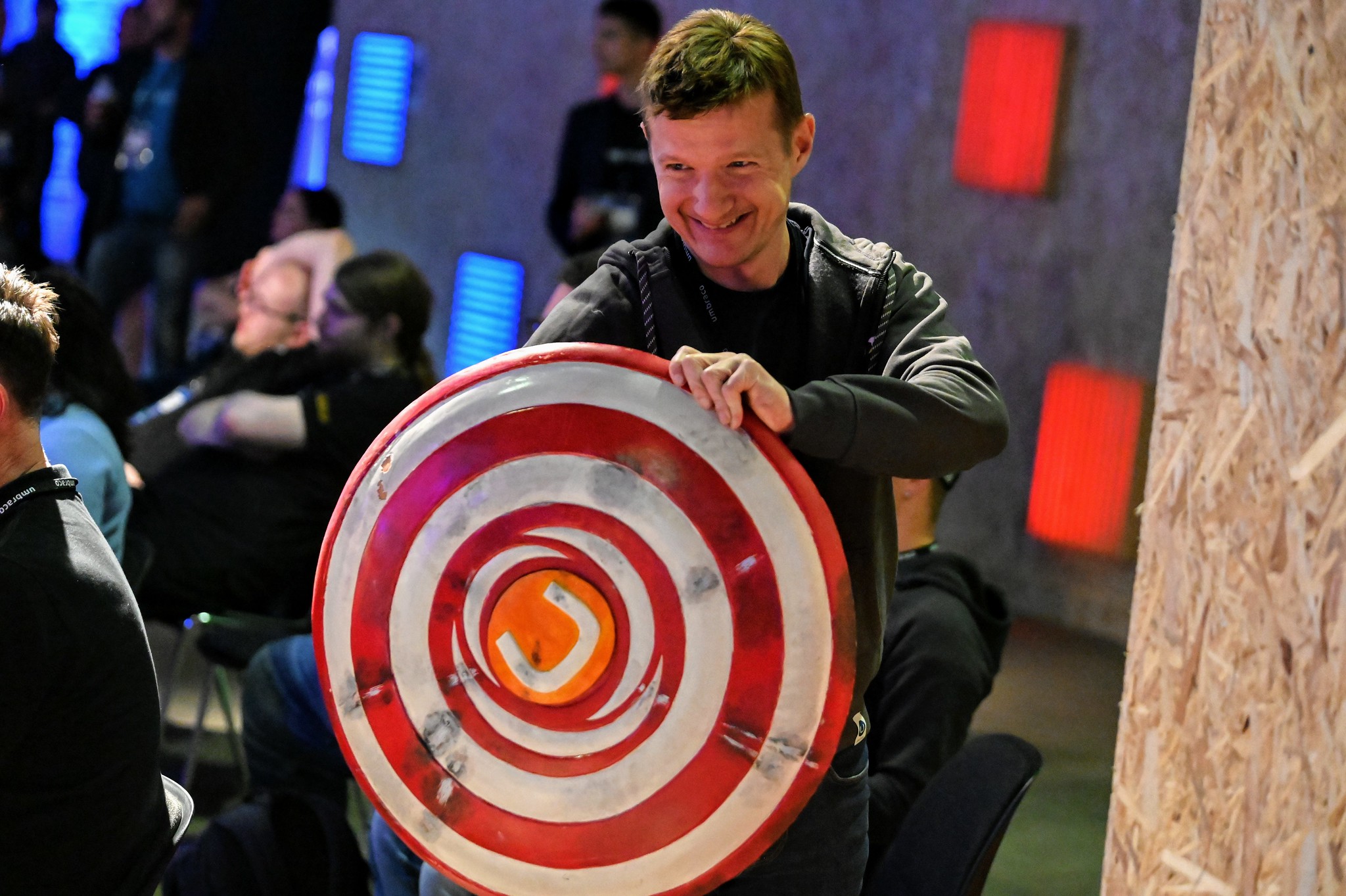 A photo by Umbraco HQ on Flickr of a man holding a Captain America-style shield with an orange Umbraco logo in the centre